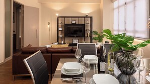 A modern dining area with a table set for two, a sofa, and a television in the background. - Lawrence House by Interhome (London City)