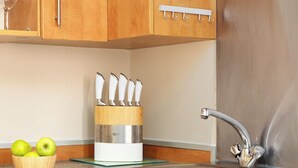 A kitchen with wooden cabinets, a knife block, a bowl of apples, and a stainless steel sink. - Lawrence House by Interhome (London City)