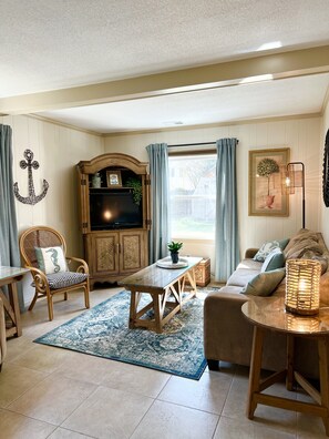 Relax in this traditional living room with a sofa, dining table, and large cabinet featuring a television.