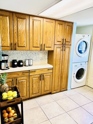 Functional kitchen with washing machine, coffee maker, and toaster.