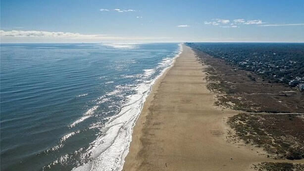 Vista aerea di una spiaggia lunga e stretta, con un chiaro confine tra la spiaggia sabbiosa e l'oceano.