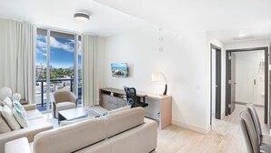 A modern hotel room with a balcony, a sofa, a desk, and a TV. - CH Luxury Spacious Beach Condo | Ocean Breeze-CS40 (Hollywood)