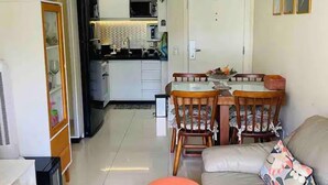 A compact living space with a kitchenette, a dining area, and a seating area with a sofa and ottoman. - The Sun (2 bedrooms in the heart of Brasilia) (DF)