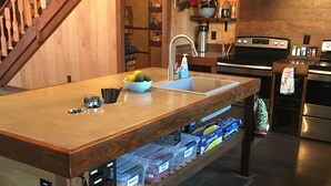 A kitchen with wooden cabinets, a built-in island with a sink, and a stove. - Fun Family Private Retreat with lighted Sports Court and Pool (Ocean View)