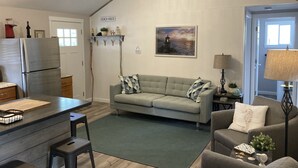 A compact living space with a kitchenette, a sofa, a dining area, and a door leading to a balcony.