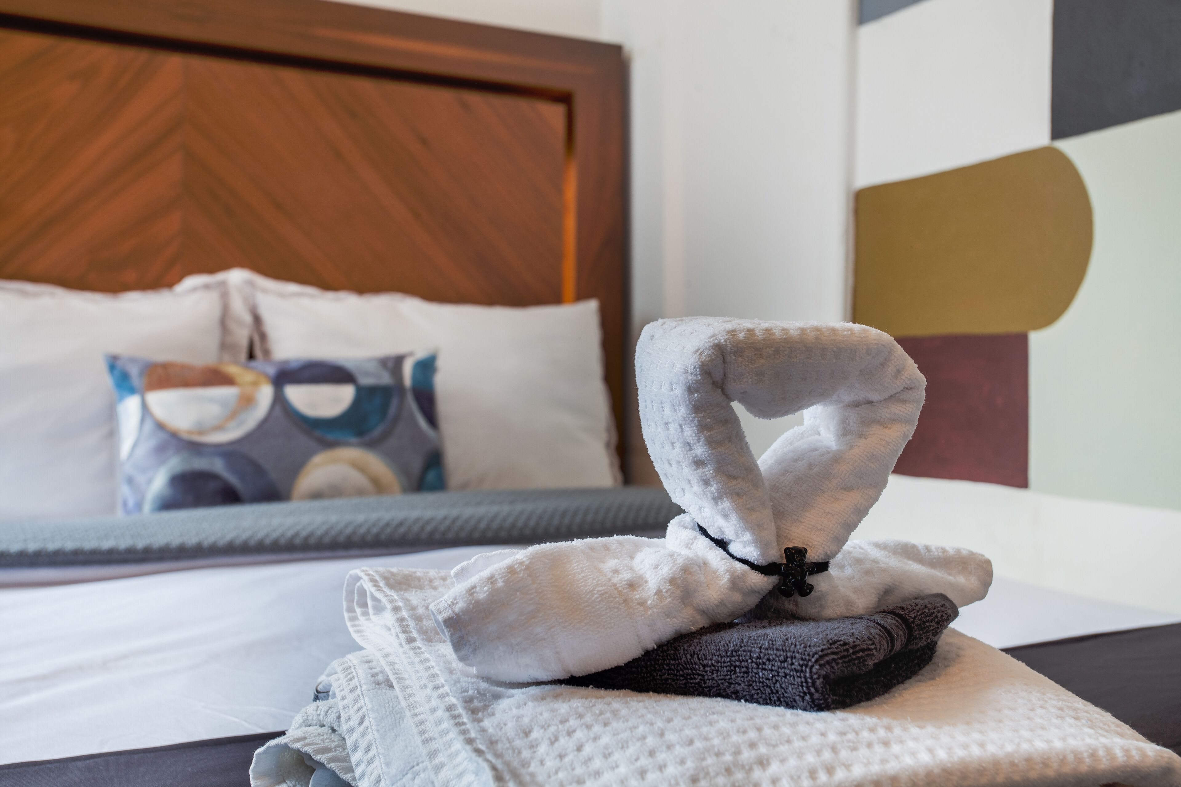 A neatly made bed with a folded towel and a blanket on top.
