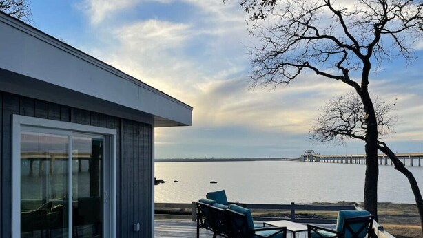 A deck with outdoor seating and a view of the water. - Rare Modern Beachfront Lake House on Lewisville Lake with Hot Tub, Deck & BEACH (Little Elm)