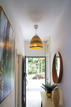 A hallway with a pendant light, a painting, a mirror, and a potted plant. - BluWaves ~ Oceanfront Condo minutes from Ocho Rios (Tower Isle)
