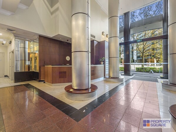Welcome to our reception area, featuring a central desk and digital clock, surrounded by large columns and a beautiful outdoor view.