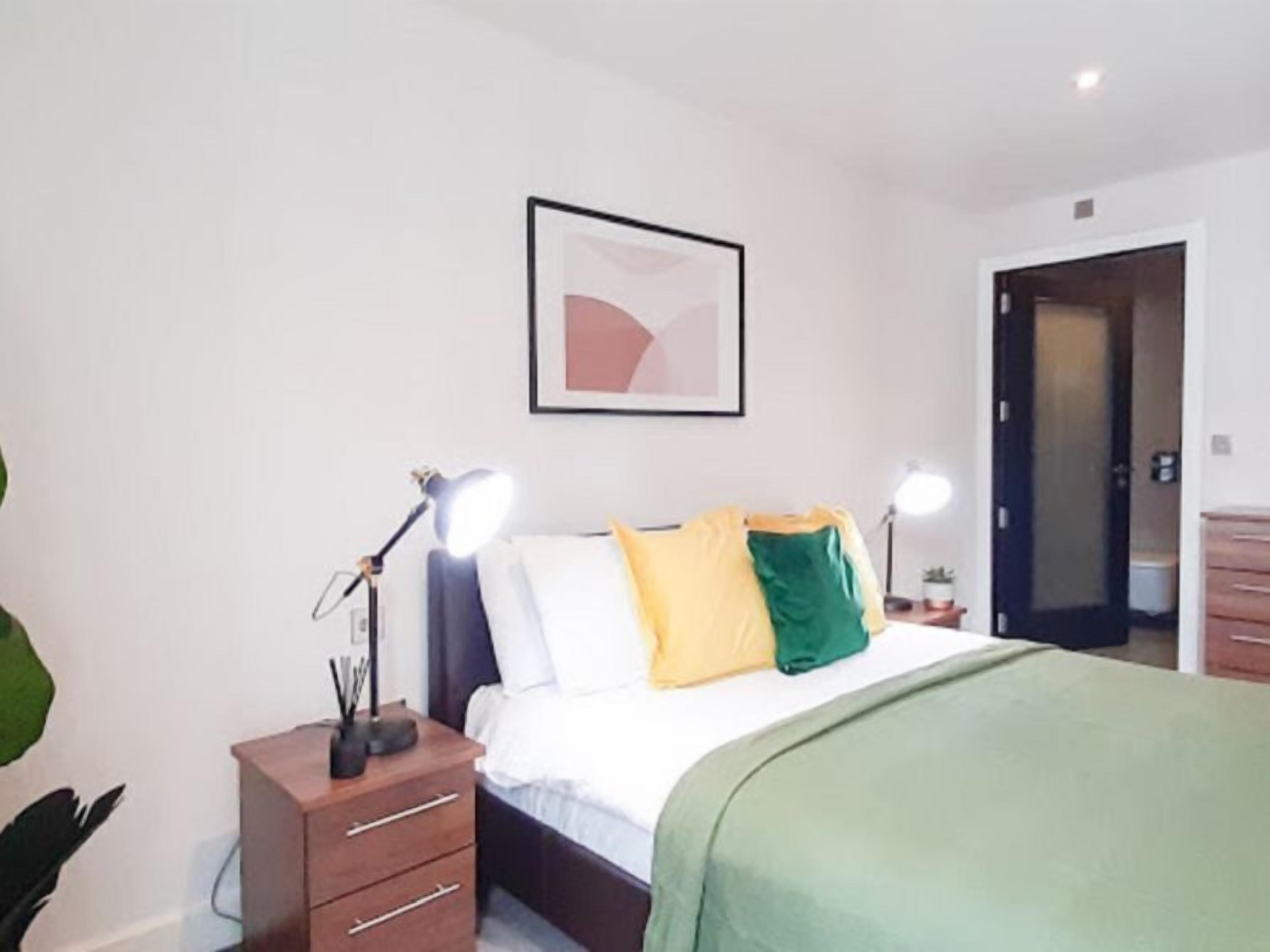 Une chambre à coucher avec un lit, des lampes de chevet, une table de chevet, une commode et une porte.
