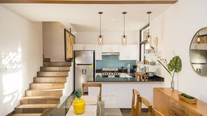 A modern kitchen with a central island, wooden staircase, and pendant lighting. - Tannah Luxury Villa Encanto (Mérida)
