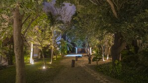 A pathway lined with trees and illuminated by soft lights, leading to a pool area. - Tannah Luxury Villa Encanto (Mérida)