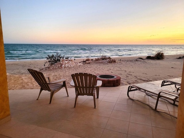 A beachside patio with chairs and a fire pit.