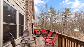 A wooden deck with outdoor seating and stone walls. - “THE ONE” Chalet, Perfect Getaway w/ Hot Tub, Multicade, Pool Table (Albrightsville)