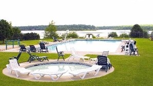 A swimming pool with lounge chairs and a view of a lake. - “THE ONE” Chalet, Perfect Getaway w/ Hot Tub, Multicade, Pool Table (Albrightsville)