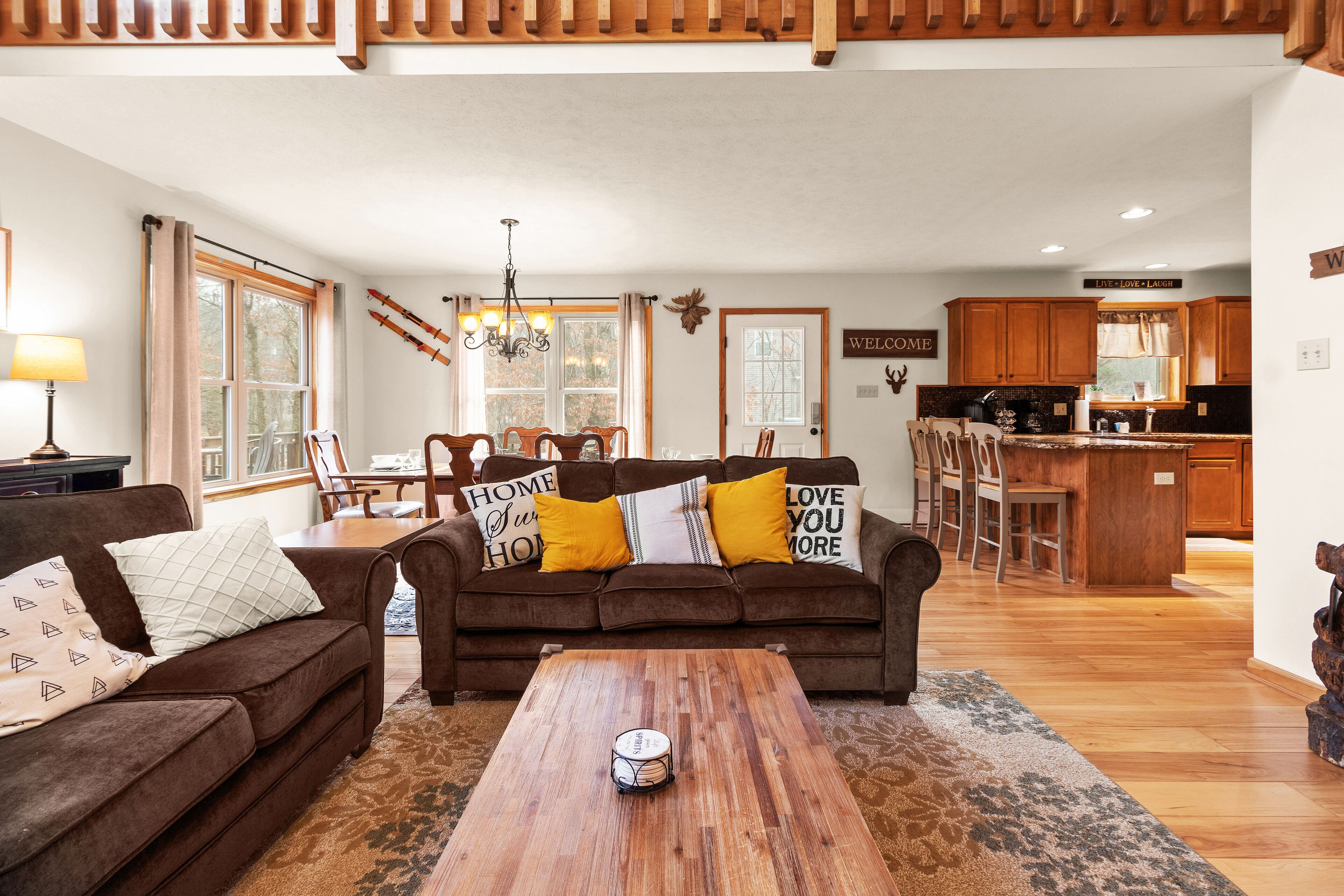 A living room with a brown sofa, a coffee table, and a dining area with chairs and a table.