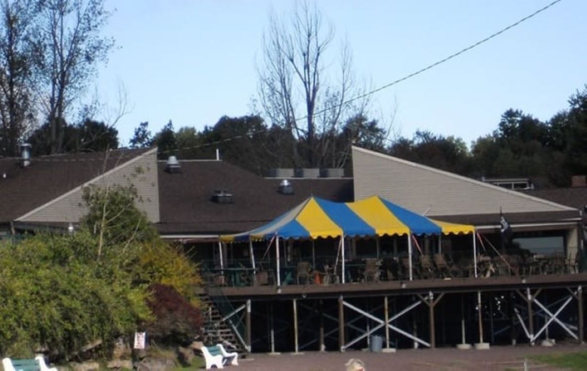 A building with a covered outdoor area, possibly a restaurant or cafe, with a blue and yellow striped awning.