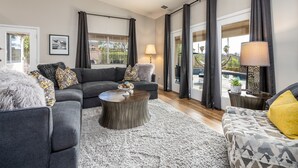 Un salon moderne avec un canapé gris, une table basse ronde et un tapis à motifs.