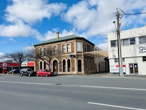 A historic building with arched windows and a brick facade, adjacent to a modern building with a sign for a bank. - 435 Ex hotel room suite in the city (Adelaide)