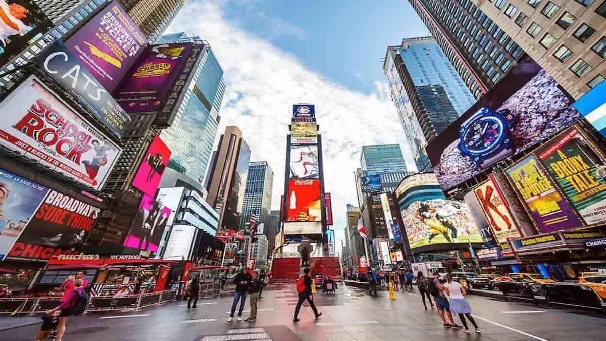 Een drukke stadstraat met hoge gebouwen, grote reclameborden en voetgangers.