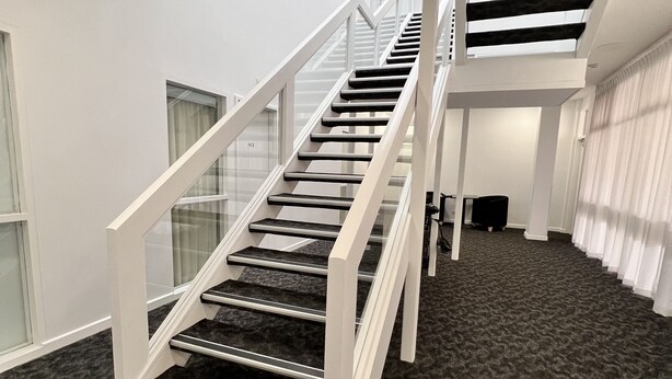 A modern staircase with glass railings leading to a second floor. - Ex hotel ensuite room at gouger st 431 (Adelaide)