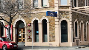A building with stone facade, arched windows, and a red car parked in front. - Ex hotel ensuite room at gouger st 431 (Adelaide)