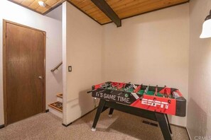 A room with a foosball table labeled "It's GAME TIME." and a wooden door.