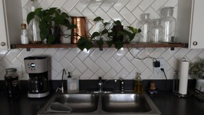 A kitchen with two sinks, a coffee maker, and a hanging light fixture.