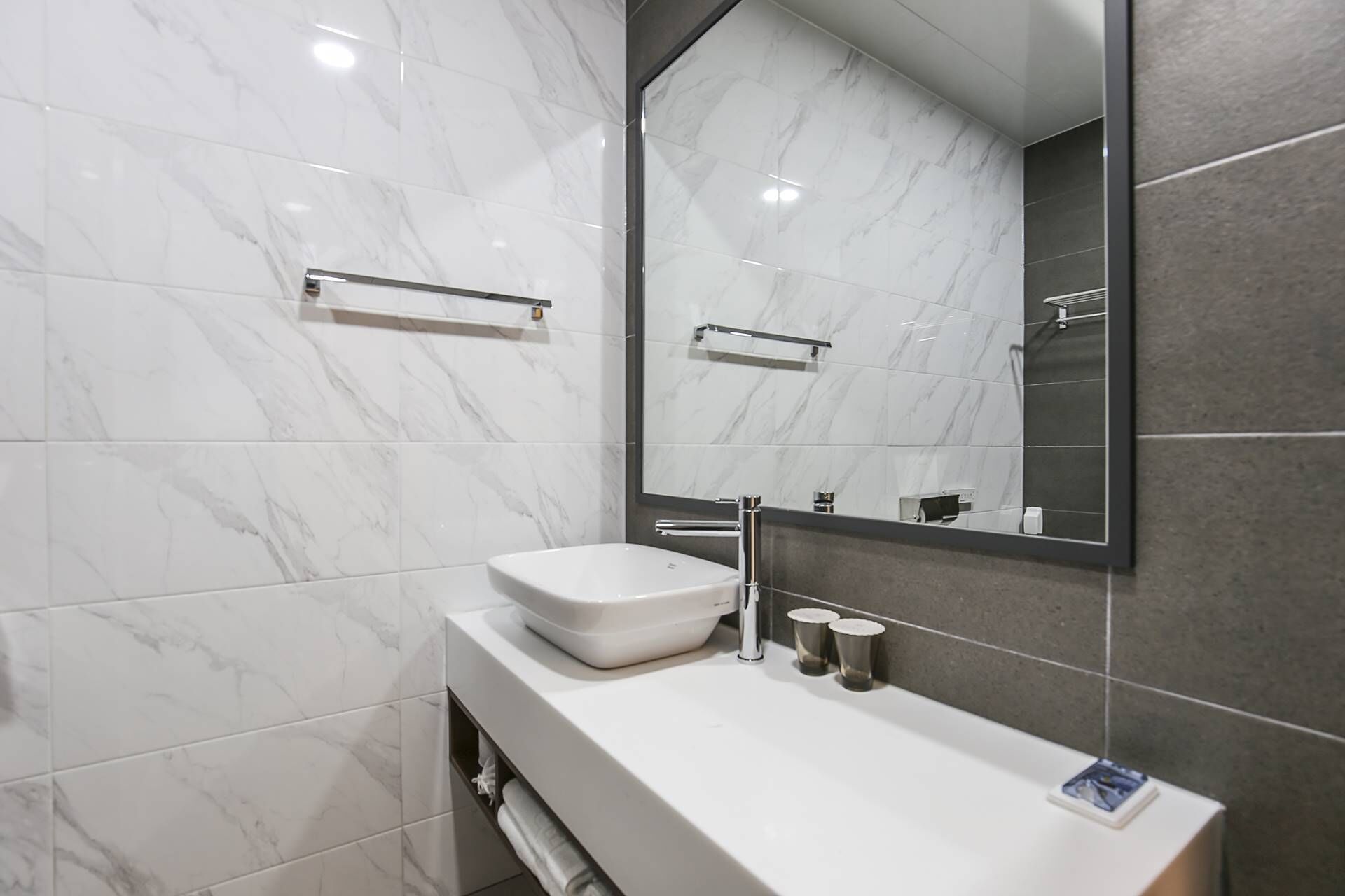 A modern bathroom with a white sink, chrome fixtures, and a large mirror.