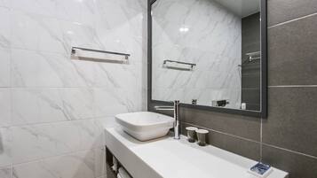 A modern bathroom with a white sink, chrome fixtures, and a large mirror.