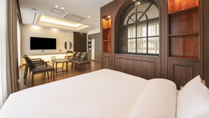 A modern hotel room with a large bed, a desk with a chair, a television, and built-in shelves. - Hotel Demer (Mokpo)