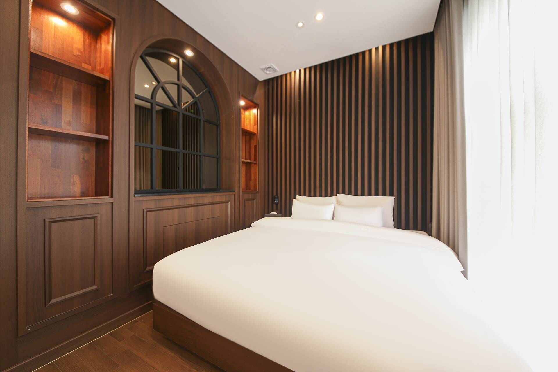Ein modernes Schlafzimmer mit einem großen Bett, Holzvertäfelung und integrierten Regalen.