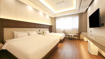A hotel room with two beds, a TV, a small table, and a chair.