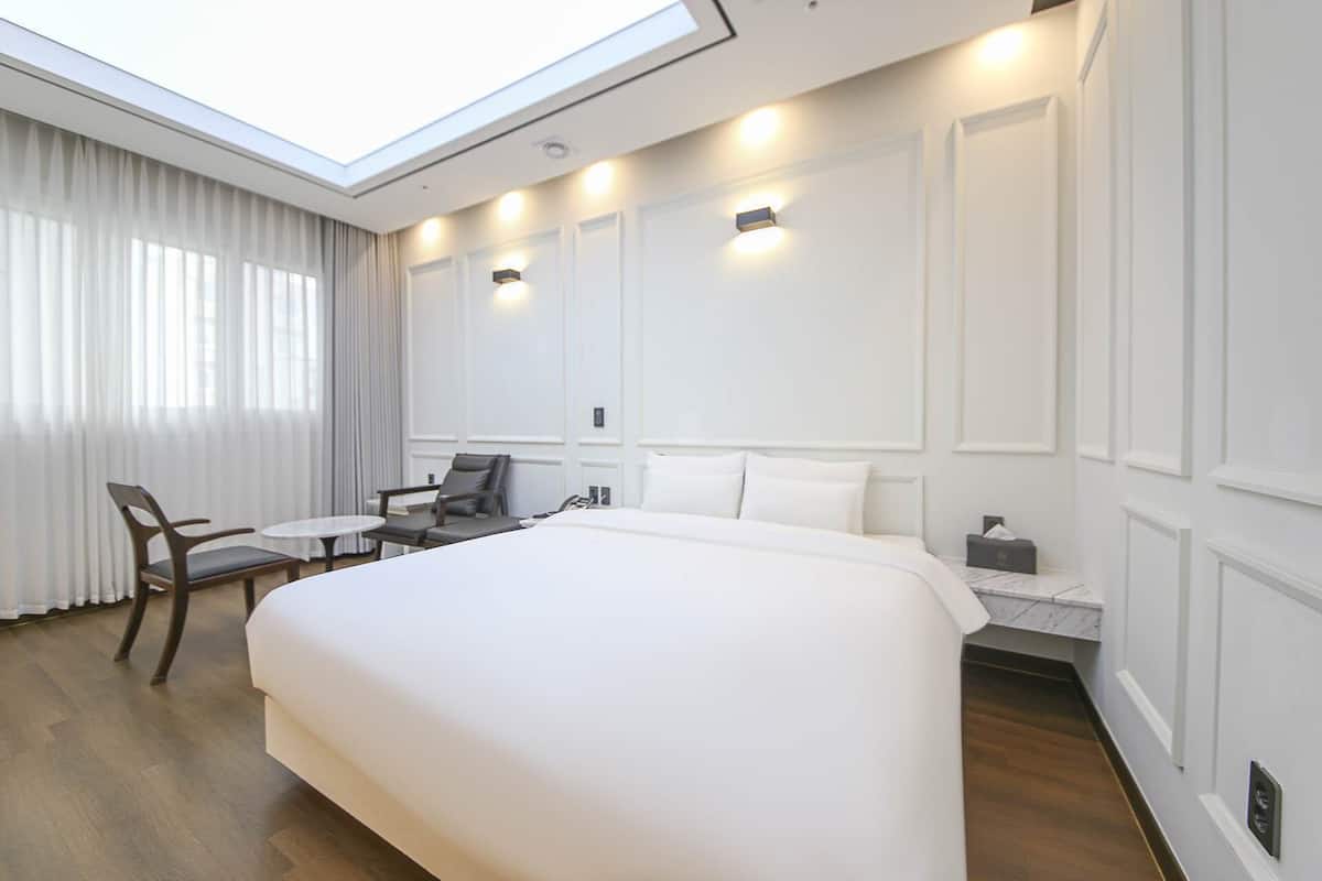 Una habitación de hotel con una cama grande, un escritorio, una silla y una mesita.