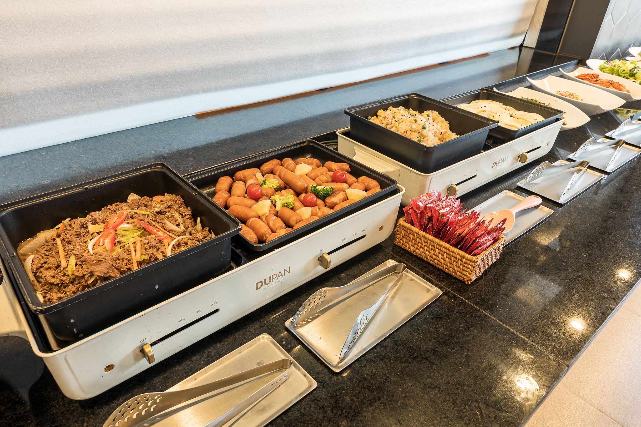A buffet with various food items including meats, vegetables, and rice dishes.