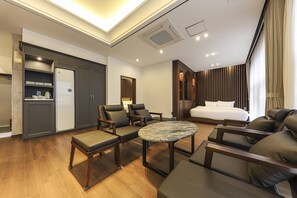 A modern hotel room with a bed, two armchairs, a round coffee table, a desk, and a wardrobe. - Hotel Demer (Mokpo)