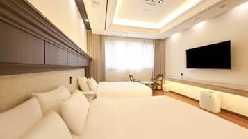 Habitación de hotel con dos camas, una televisión de pantalla plana, una mesita pequeña y una silla.