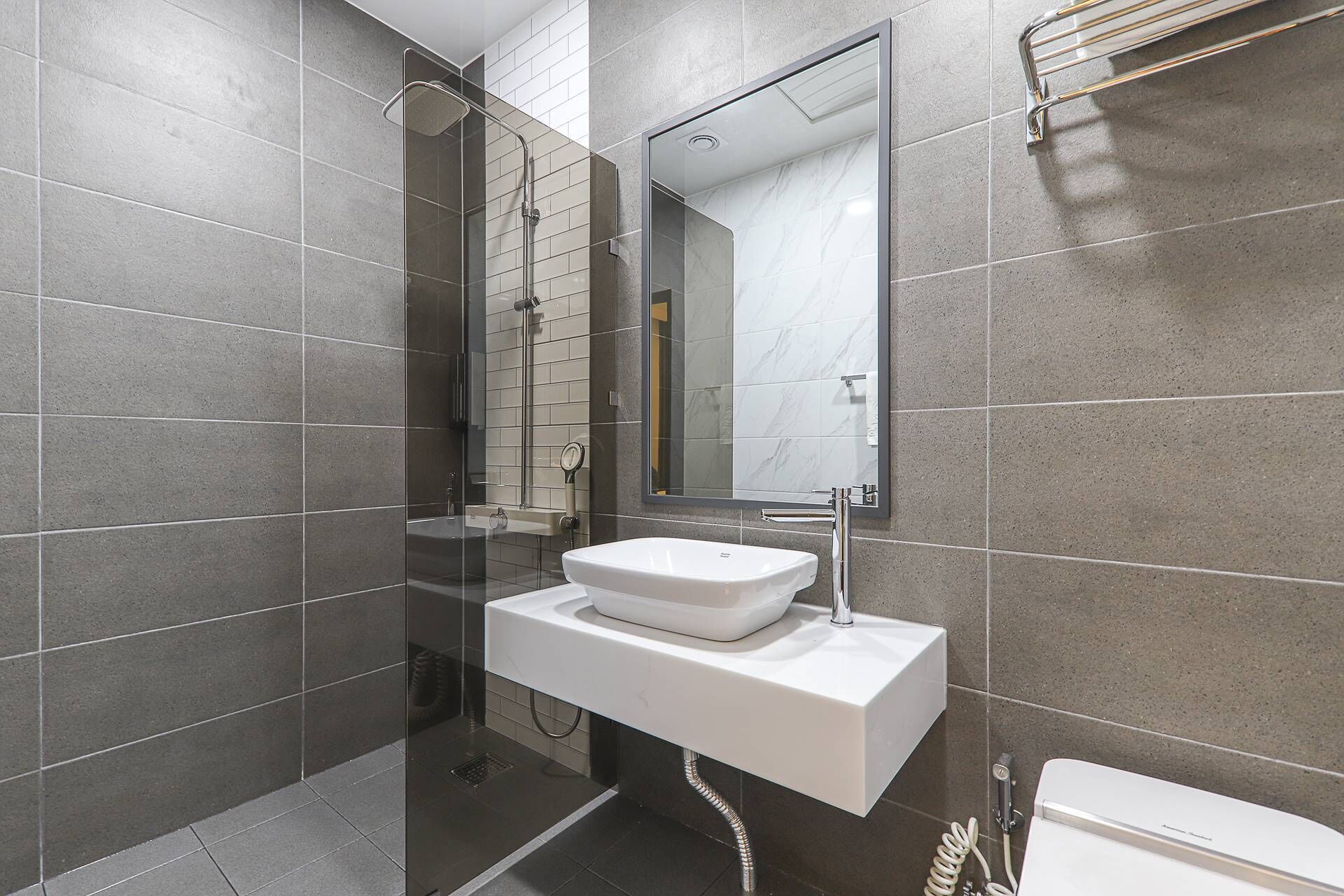 A modern bathroom with a white sink, a glass-enclosed shower, and a large mirror.