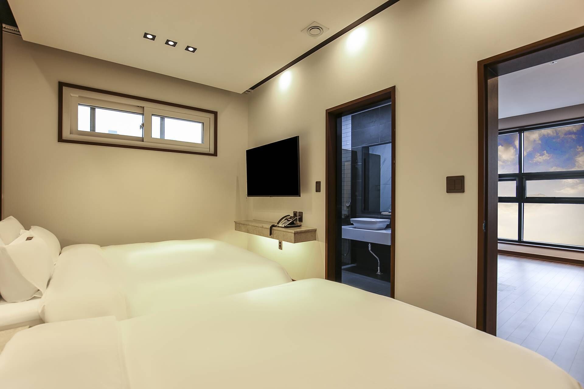 Een moderne hotelkamer met een groot bed, een televisie, een badkamer met een wastafel en een raam met uitzicht.