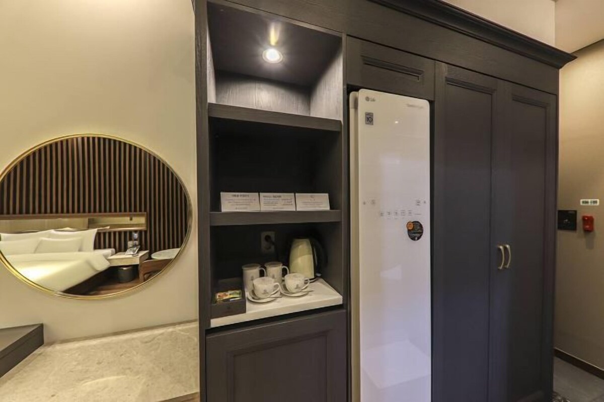 A modern kitchen with a built-in refrigerator, a coffee machine, and a mirror.