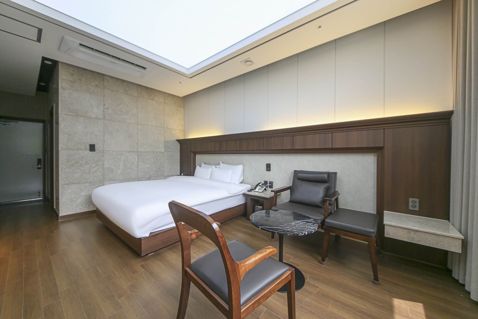 Una habitación de hotel con una cama grande, un escritorio con una silla y una mesita.