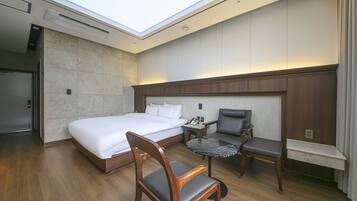 Una habitación de hotel con una cama grande, un escritorio con una silla y una mesita.