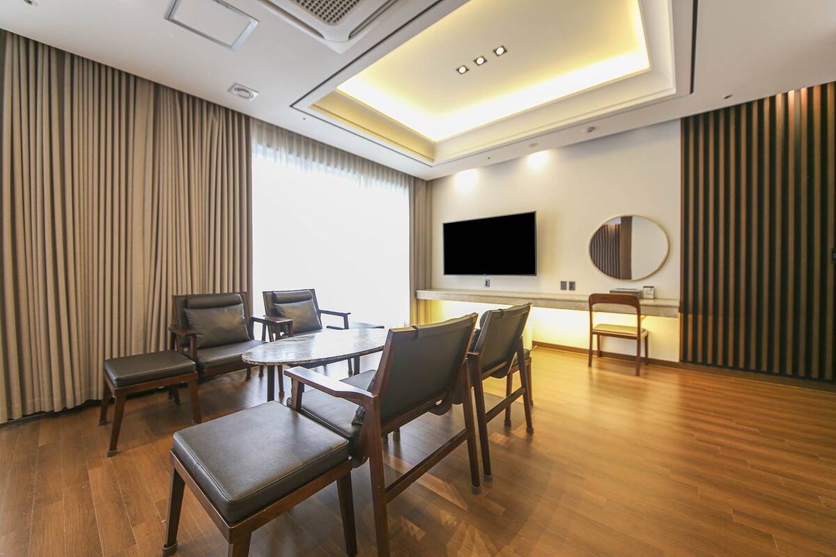 Un salón de conferencias con una mesa grande, varias sillas, una televisión y un espejo en la pared.