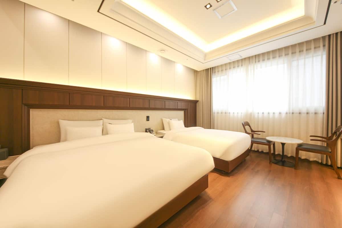 Una habitación de hotel con dos camas, una mesita y una silla.