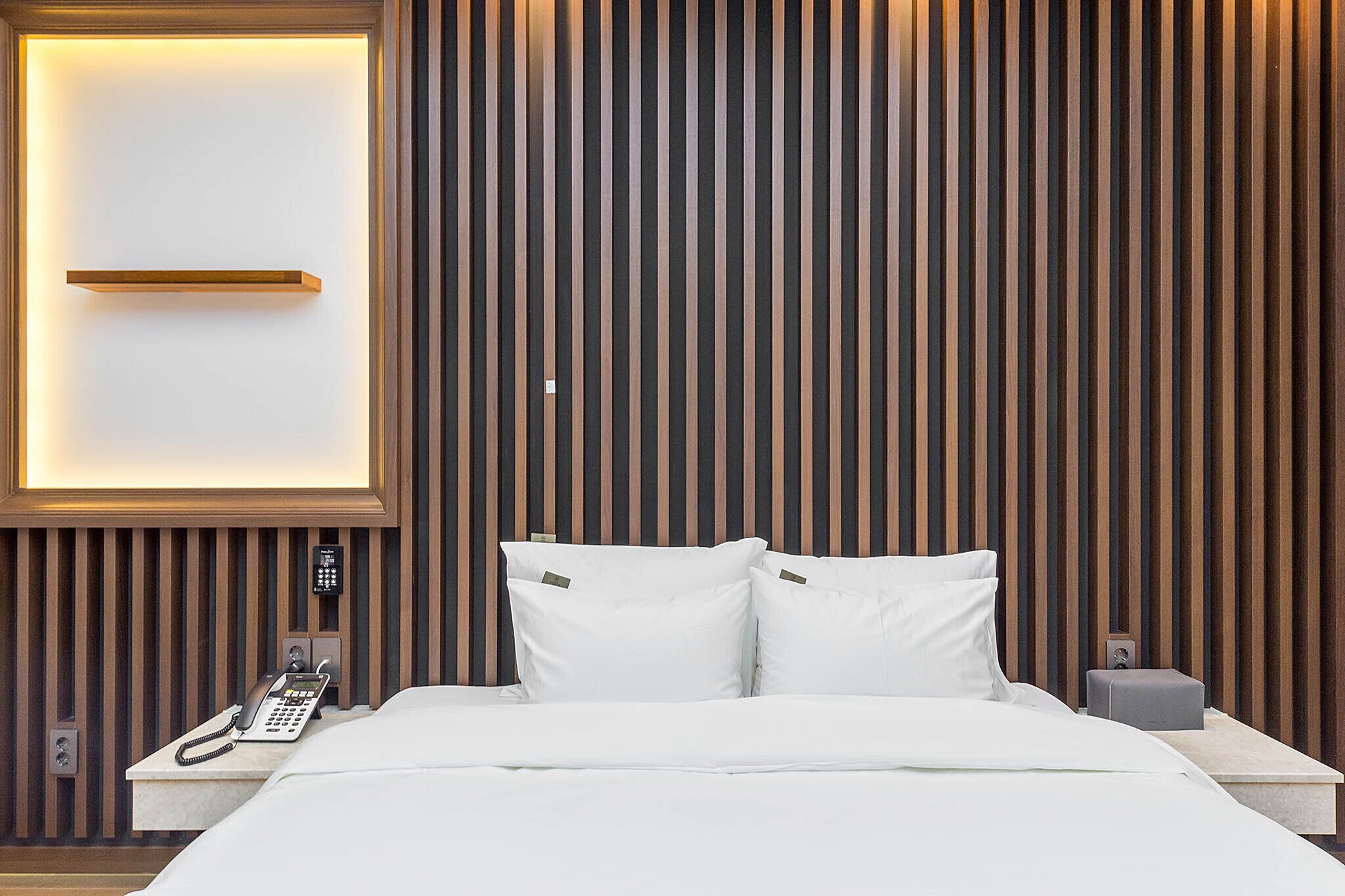 A hotel room with a bed, a bedside phone, and a nightstand.