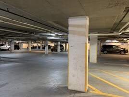 Uma garagem de estacionamento com vários níveis, pilares de concreto e linhas de demarcação amarelas.