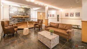 Un moderno vestíbulo con chimenea de piedra, muebles de cuero y suelo de baldosas.