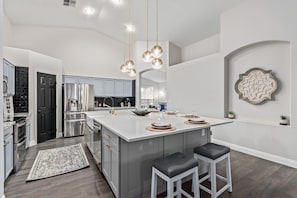 A modern kitchen with a large island, stainless steel appliances, and a decorative wall piece.