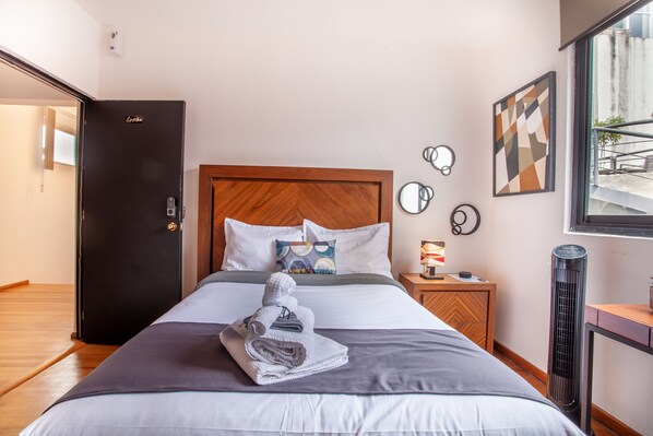 Une chambre d’hôtel avec un lit, une table de chevet, un radiateur et une porte.