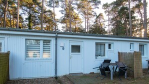 A white mobile home with a number '9' on the door, a small porch with two chairs, and a wooden fence. - Double room 17 - Ferienanlage Zum Knirk (Lubmin (Seebad))